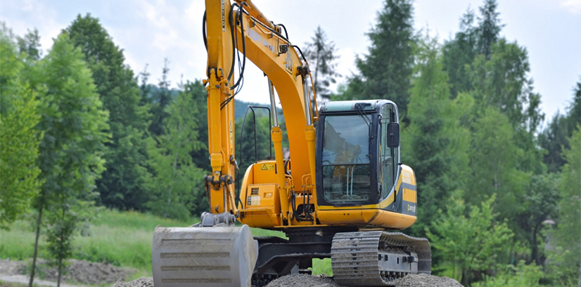 Yellow excavator with trees in the background.